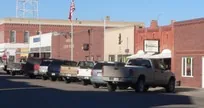 Pickup trucks parked outside brick buildings on a small-town main street