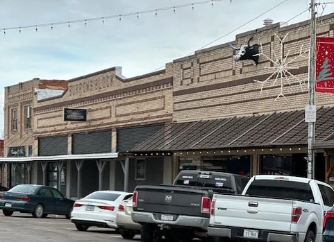 Historic brick storefront block with pickup trucks parked along the street