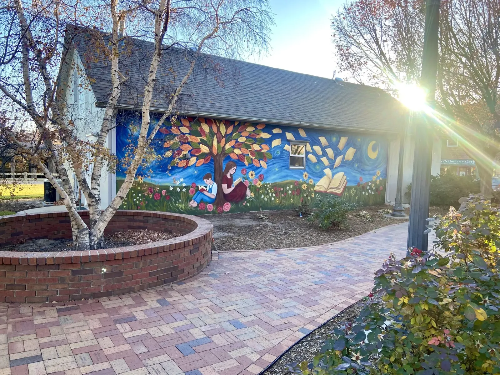 Colorful reading mural beside a brick courtyard and birch trees