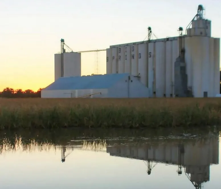 Grain elevator reflected in water at sunset