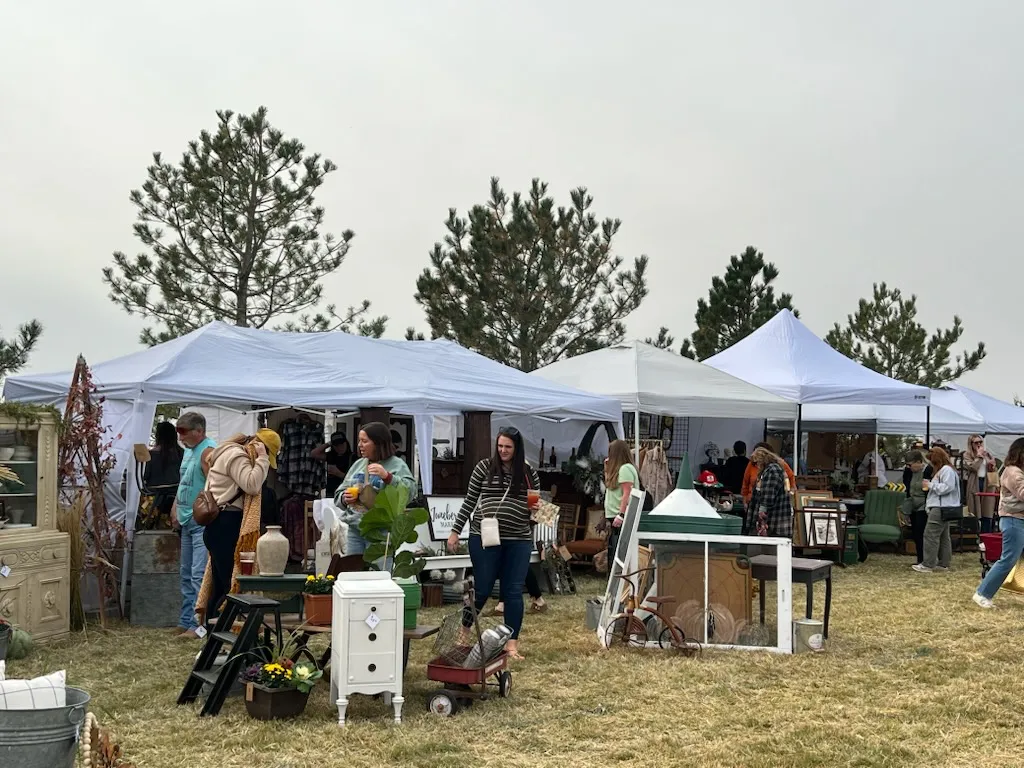 Shoppers browsing white vendor tents at an outdoor market